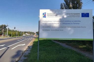 Tablice informujące o współfinansowaniu ze środków POIiŚ stoją na początku i na końcu przebudowywanej drogi tablica